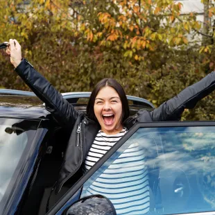 Woman celebrating with new car.