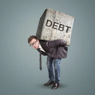 man wearing a suit and glasses with a rock on his back that says DEBT.