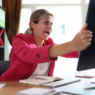 woman wearing pink blazer grabbing a computer monitor