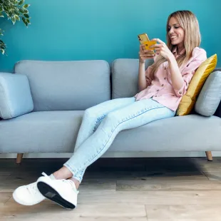 woman sitting on couch holding phone